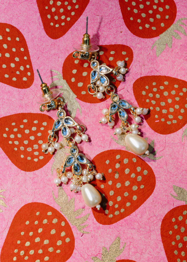 Colorful wedding stationery with bridal earrings arranged in a playful flat lay for wedding details photographs.