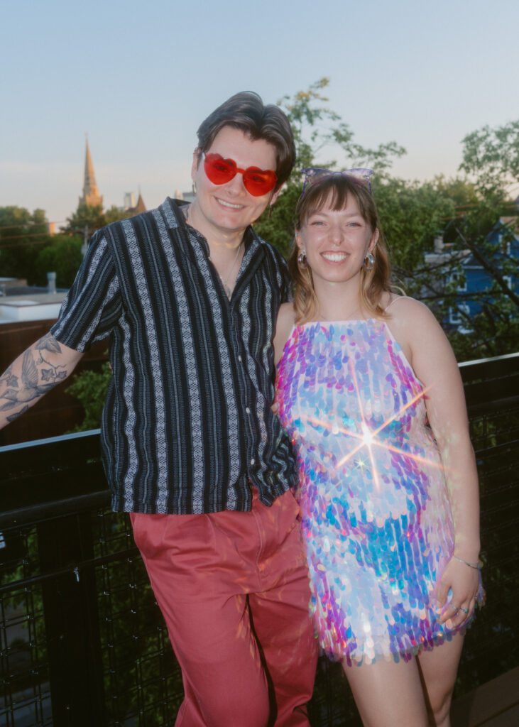 Wedding guests wearing colorful attire pose together on the rooftop patio during cocktail hour at Solar Arts Building in Minneapolis.
