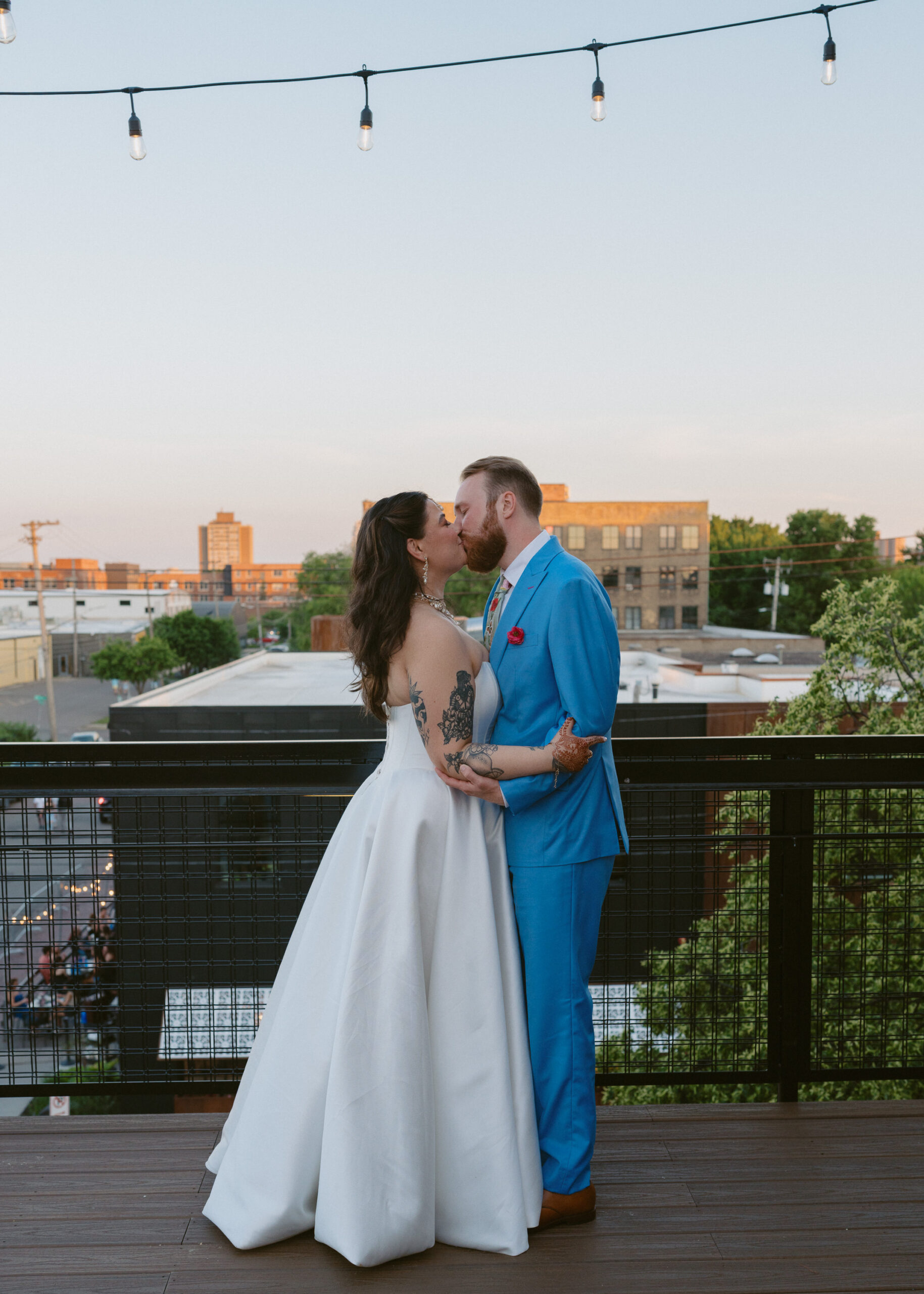 Bride and groom share a kiss during golden hour rooftop portraits overlooking Minneapolis after their wedding ceremony.