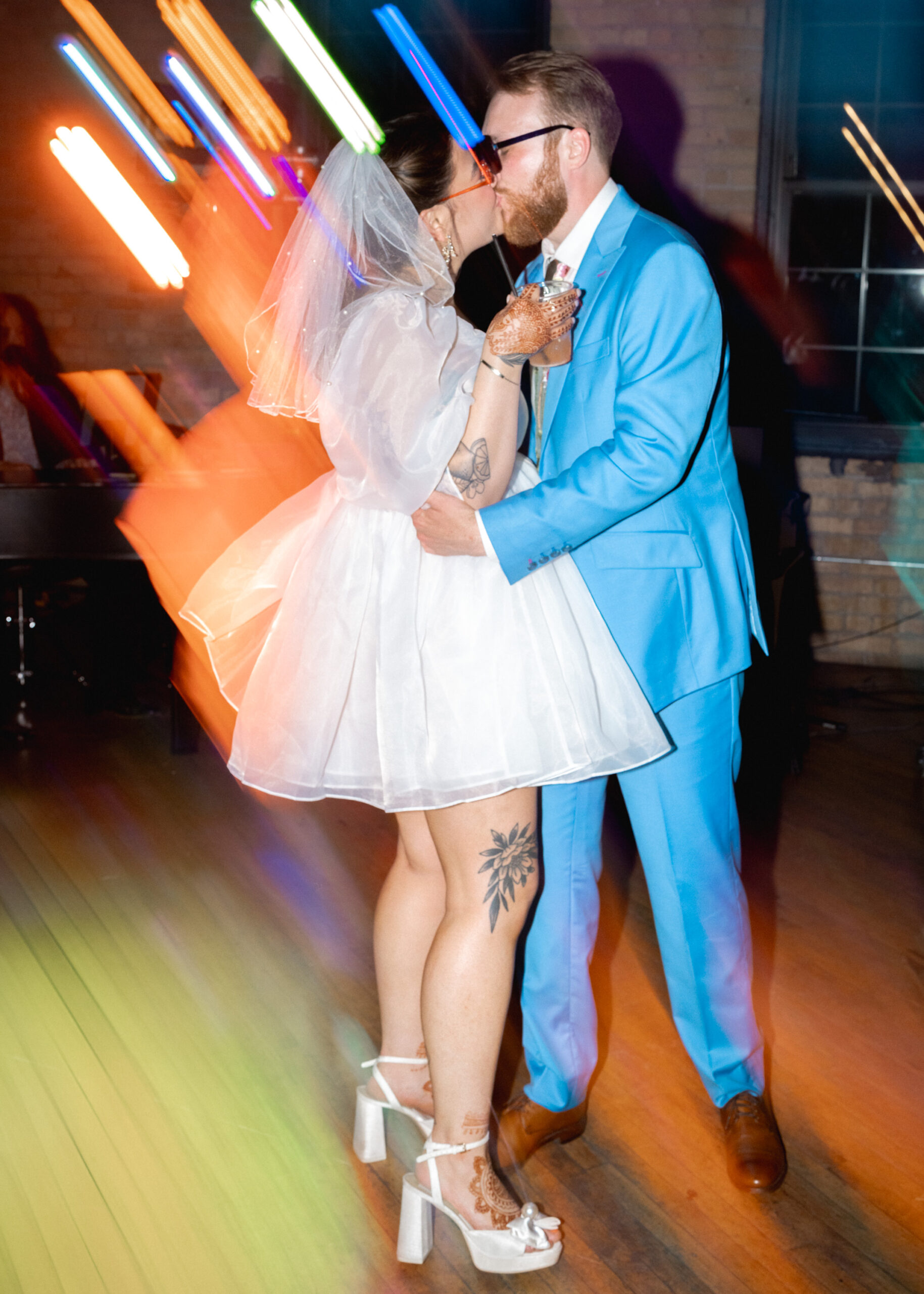 Bride and groom share a dance surrounded by colorful lights during their wedding reception at Solar Arts Building.
