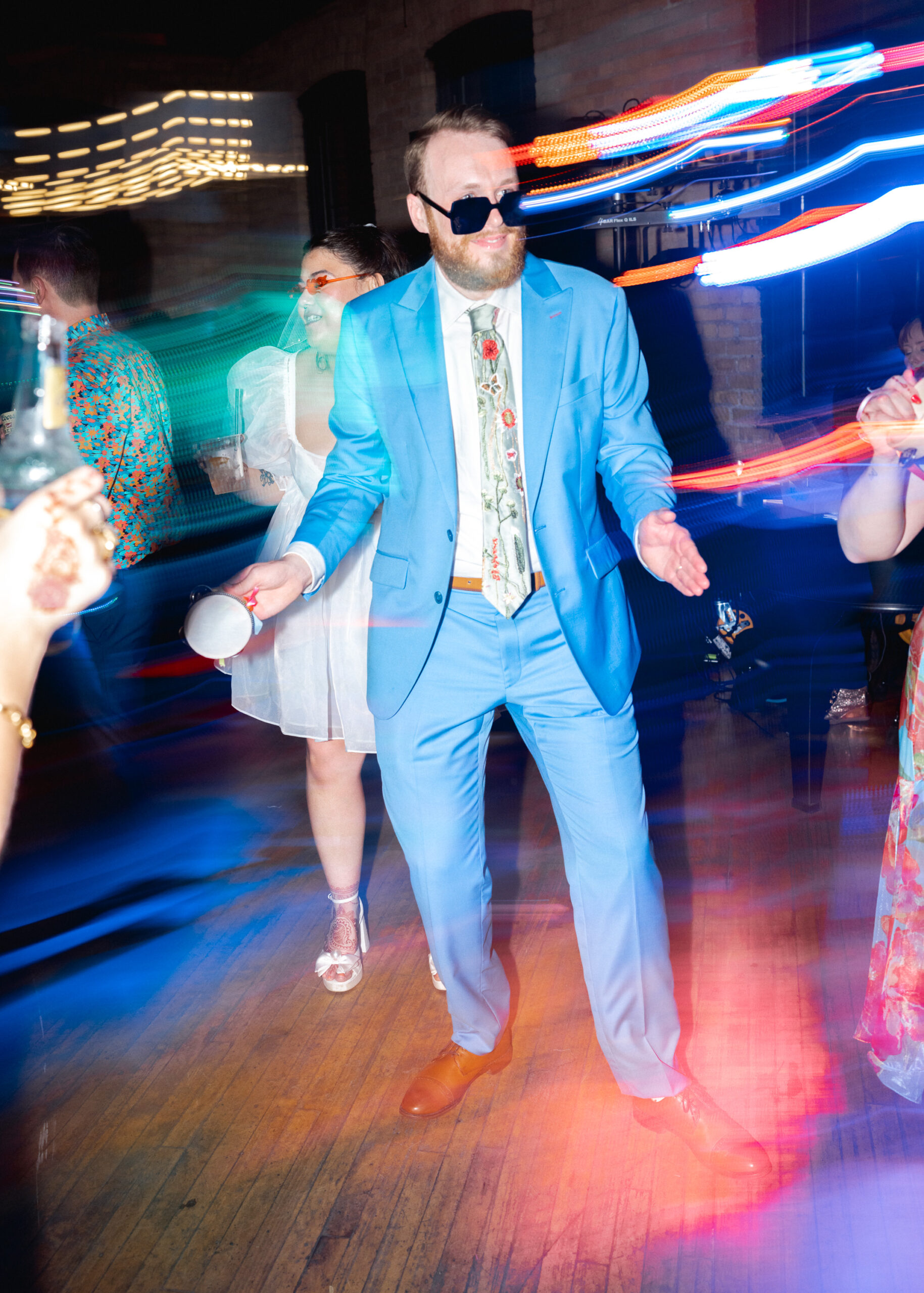 Groom dances on the reception dance floor with colorful motion blur lighting at Solar Arts Building in Minneapolis.