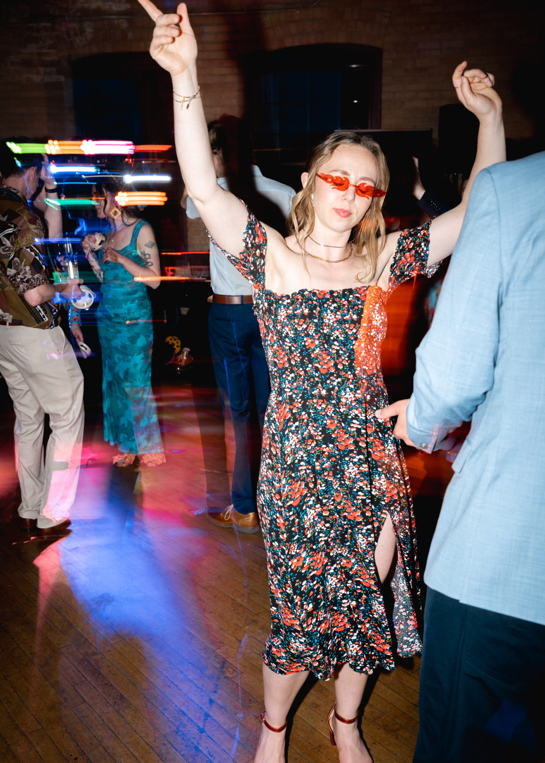 Wedding guest dances on the reception dance floor wearing red sunglasses at Solar Arts Building in Minneapolis.