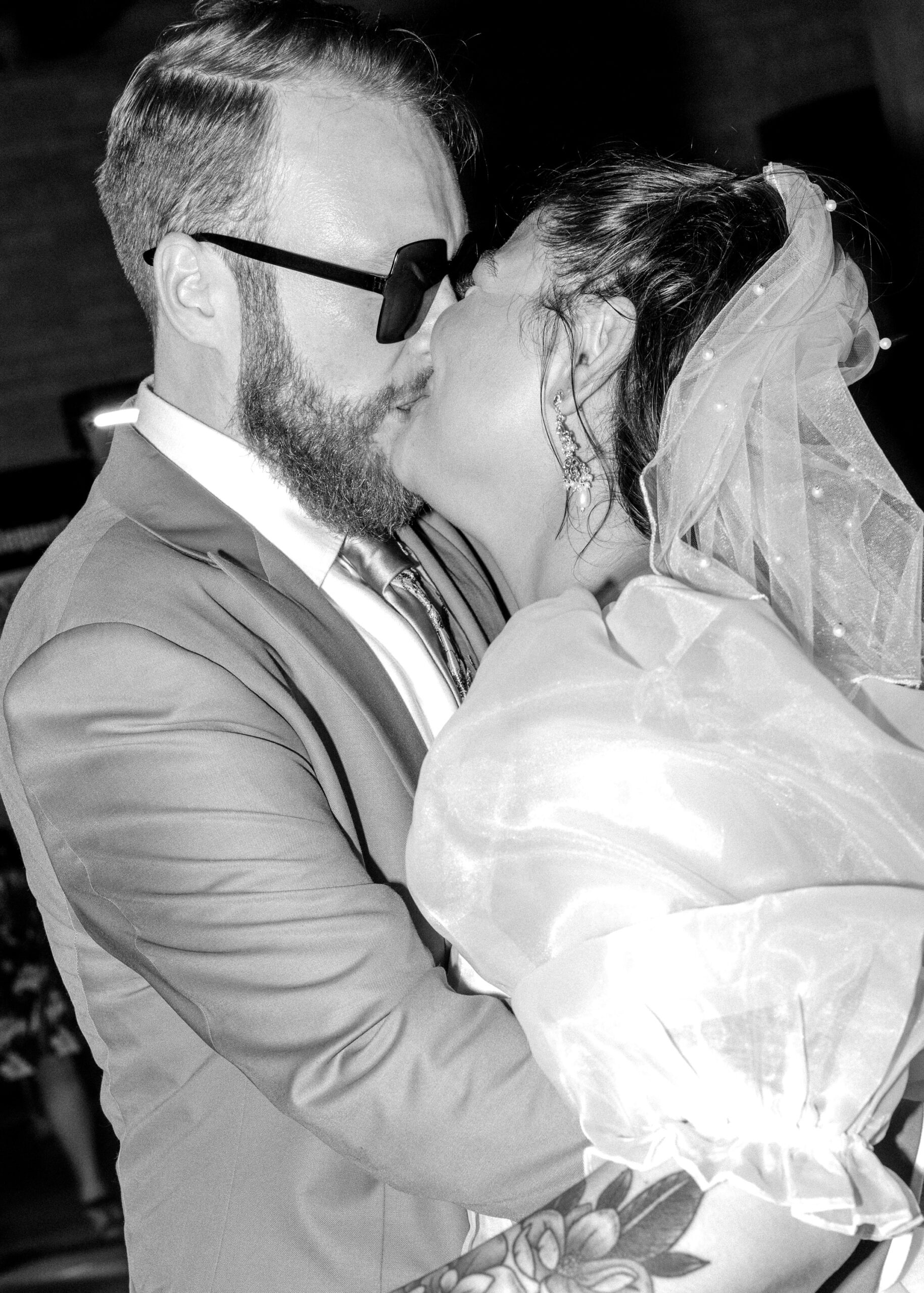 Black-and-white photo of the bride and groom sharing a kiss during their wedding reception at Solar Arts Building.
