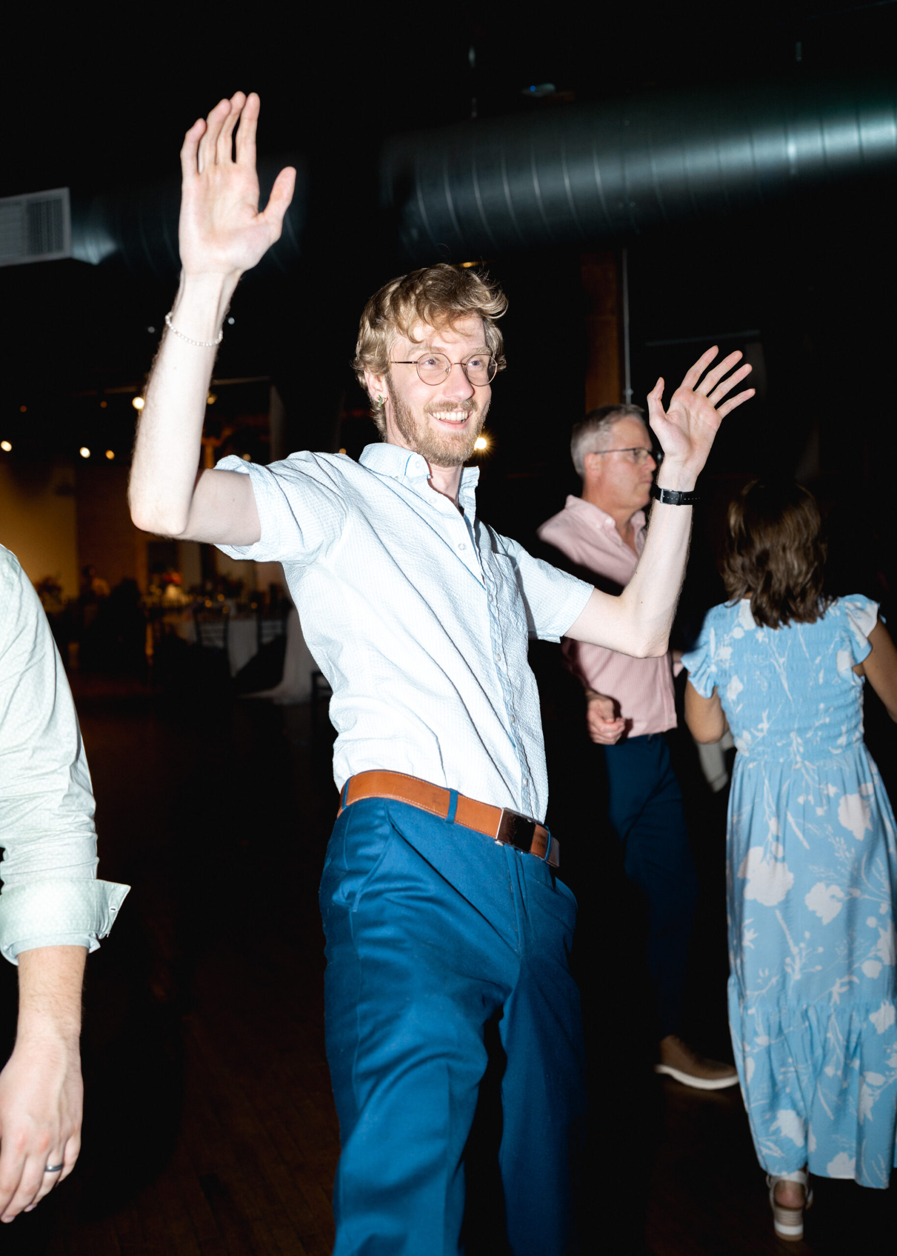 Wedding guest raises his hands while dancing during the reception celebration at Solar Arts Building in Minneapolis.