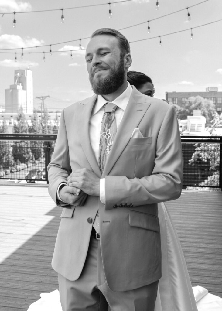 Groom waits with his back turned and smiles before seeing his bride during their first look.