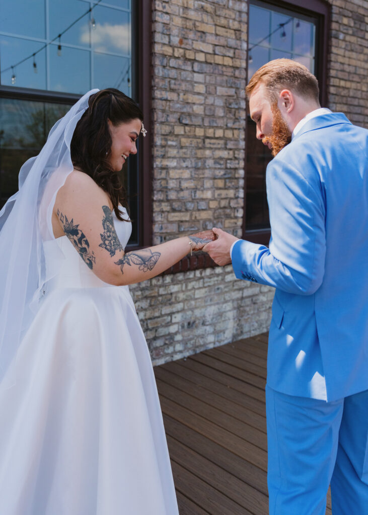 Bride holds out her henna-covered hands as the groom searches for his hidden initials during their first look.
