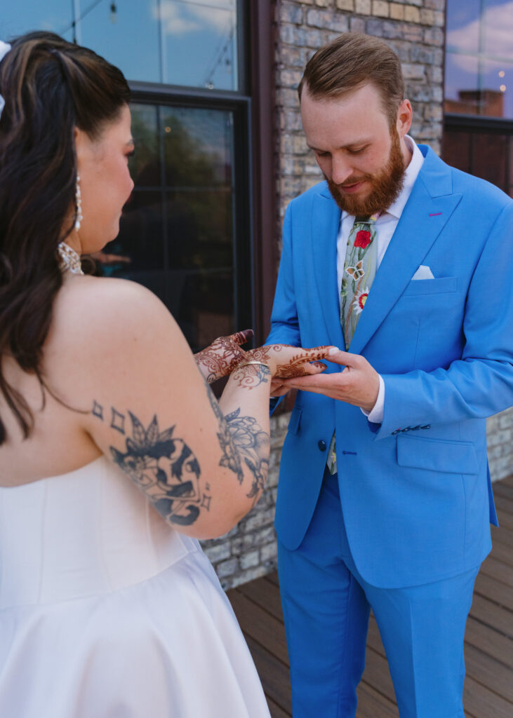 Bride holds out her henna-covered hands as the groom searches for his hidden initials during their first look.