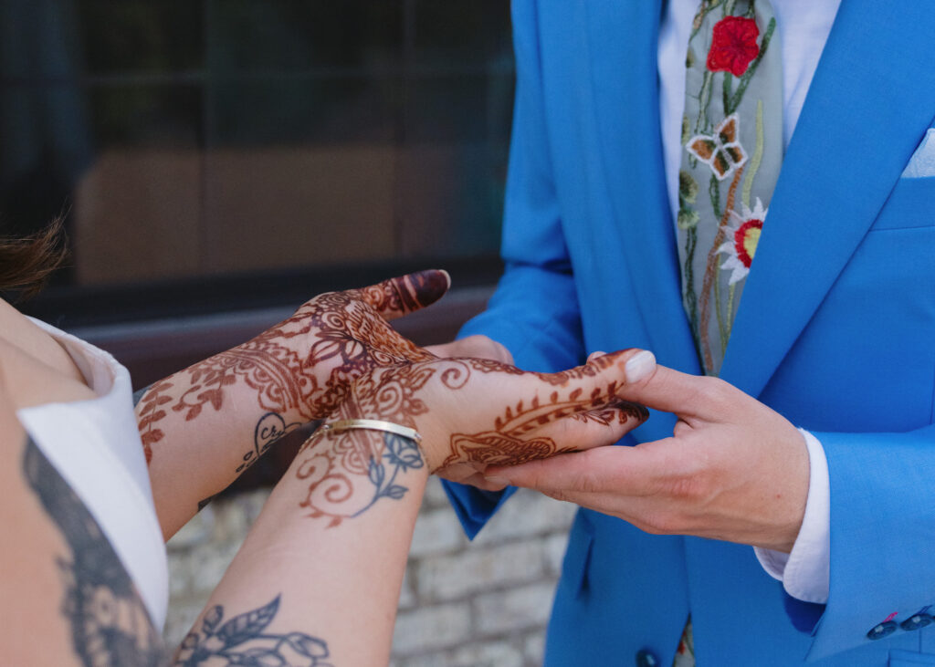 Close-up of the groom searching for his hidden initials in the bride’s detailed wedding henna.