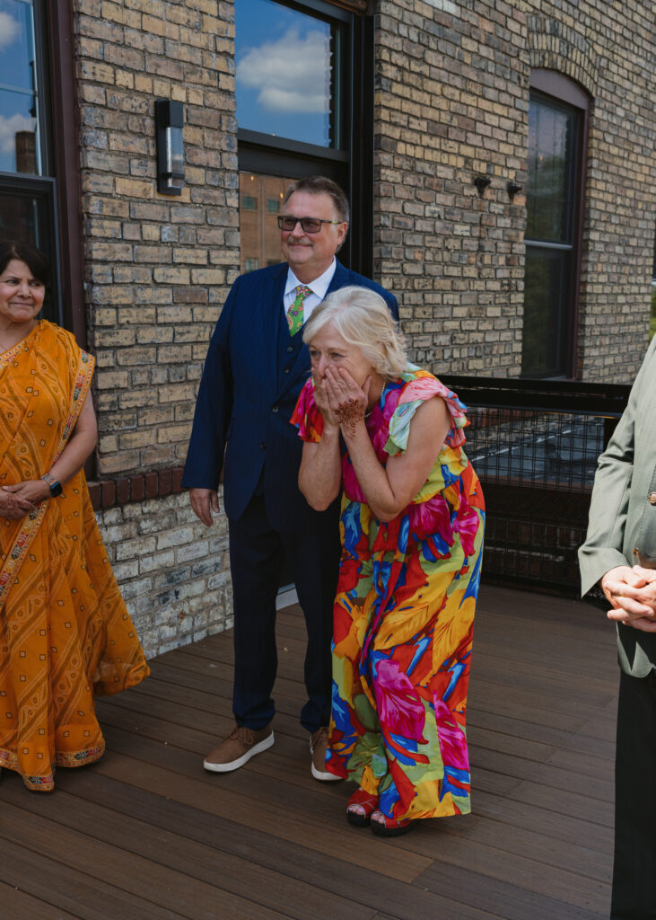 Groom’s mother smiles with emotion as she sees the bride for the first time during their wedding day first look.