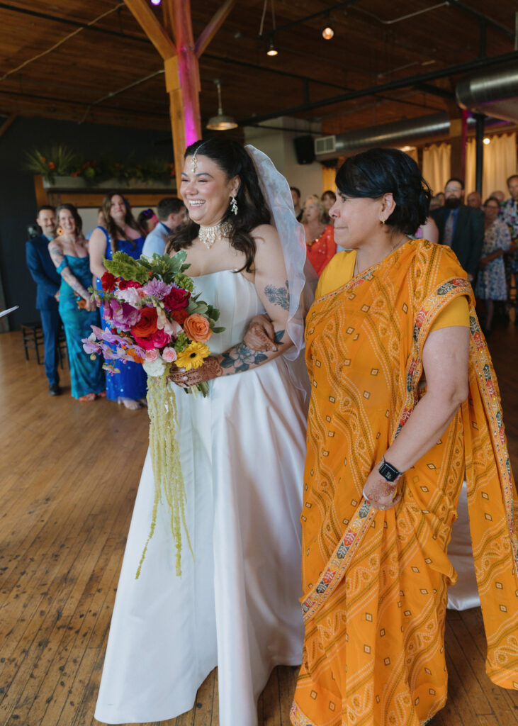 Bride smiles beside her mother while holding her colorful bouquet before the wedding ceremony.