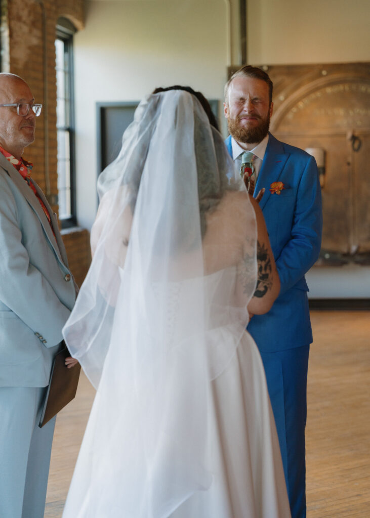 Bride and groom smile through tears while exchanging their wedding vows during the ceremony.
