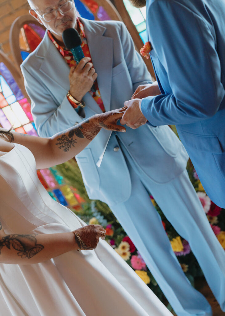 Bride and groom exchange wedding rings during their ceremony.