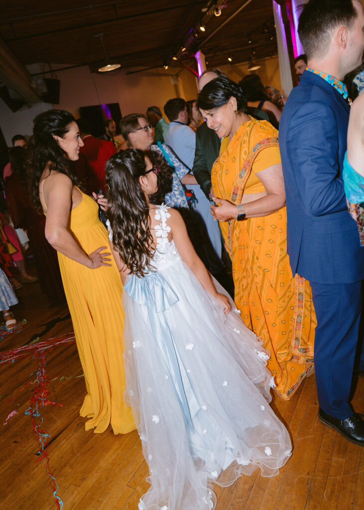 Bride's mom chats with guests during cocktail hour while family and friends celebrate around