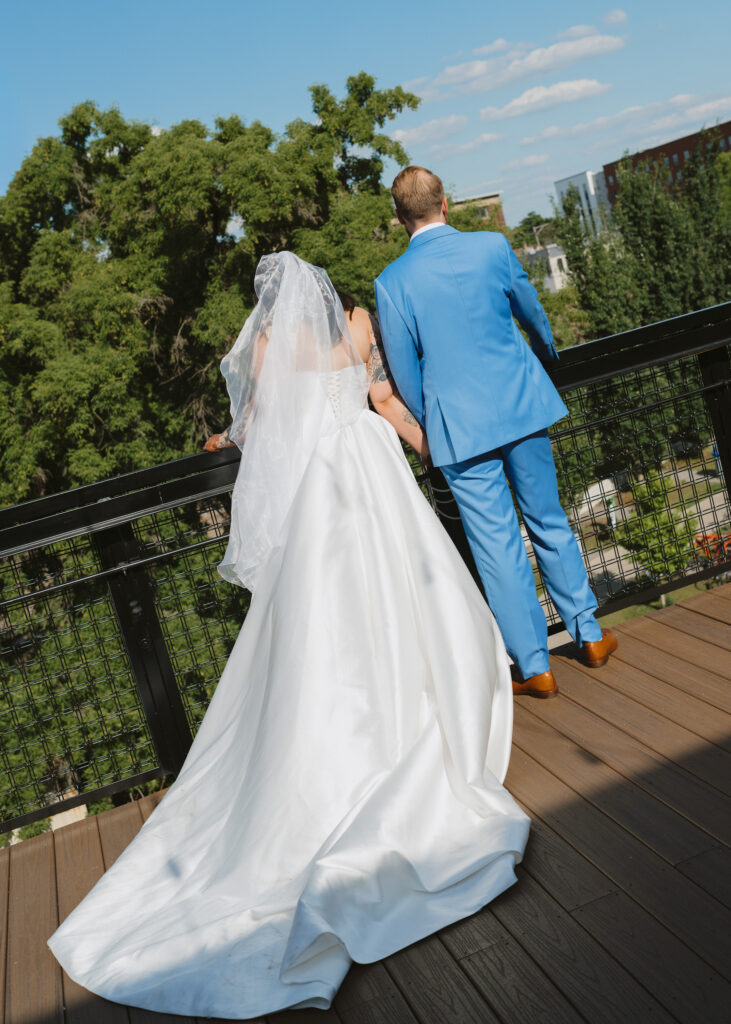 Bride and groom walk hand in hand across a rooftop terrace after their wedding ceremony.