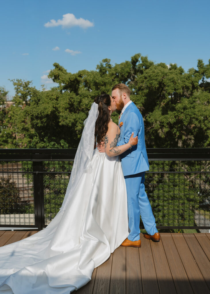Bride and groom embrace on a rooftop terrace following their wedding ceremony.