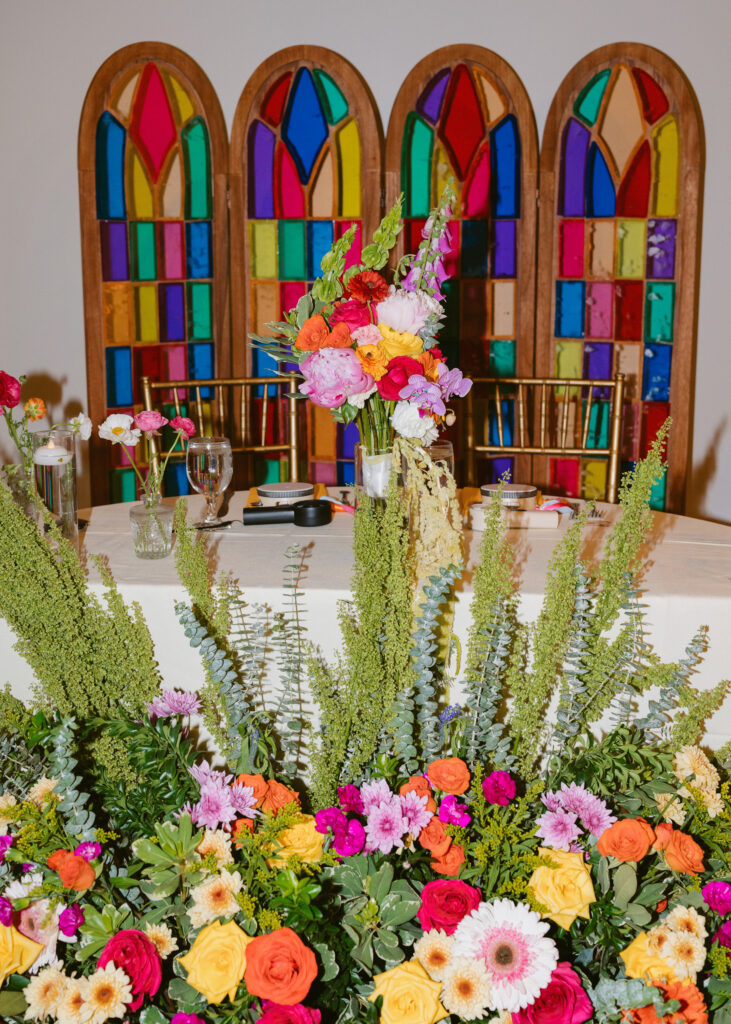 Colorful floral ceremony backdrop with stained-glass-inspired panels at the Solar Arts Building wedding reception