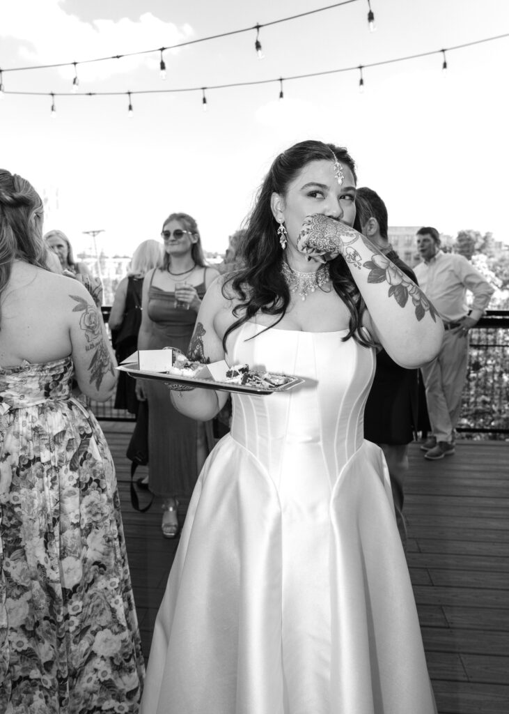 Bride smiles while enjoying snack with guests during the wedding reception.