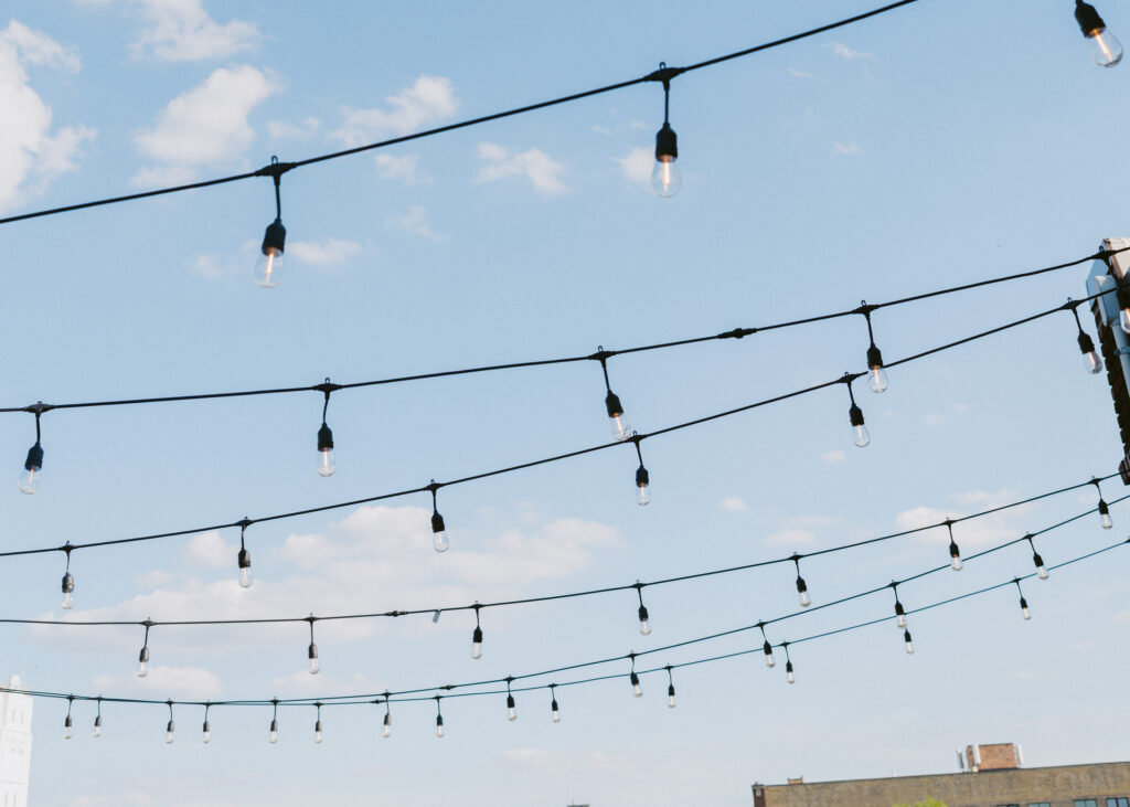 String lights hanging overhead against a blue evening sky outside the Solar Arts Building.