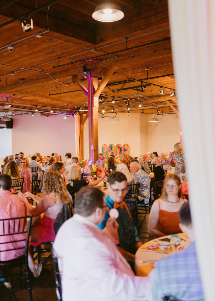 Guests gather around colorful tables during the wedding reception at the Solar Arts Building.