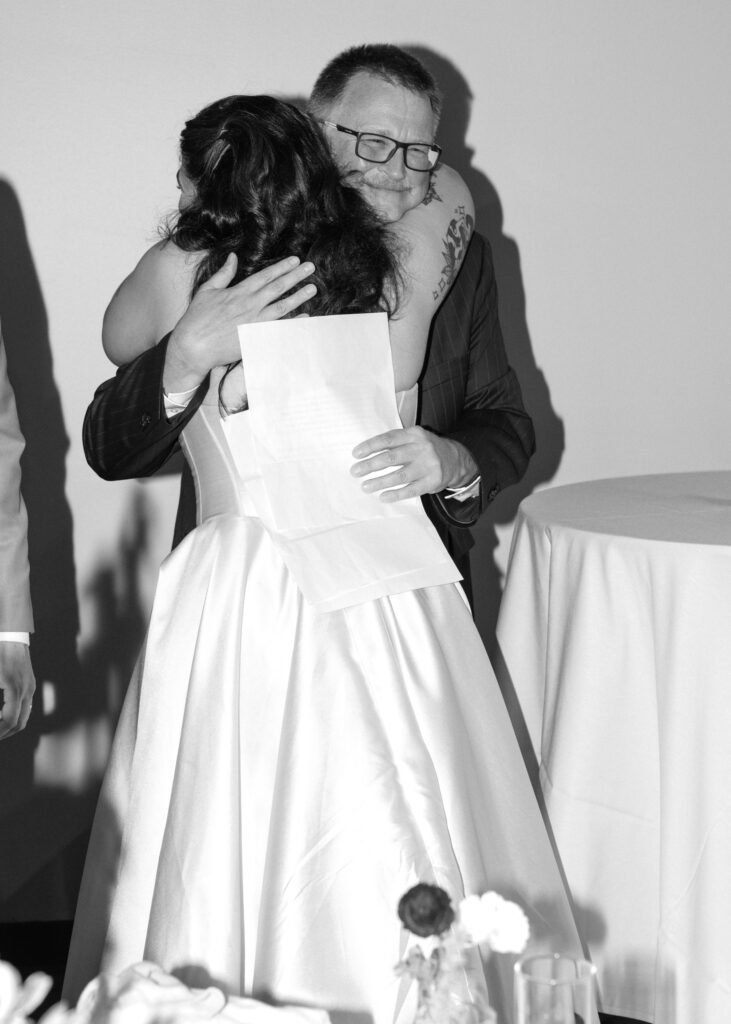 Bride hugs her new father-in-law during an emotional moment at the wedding reception