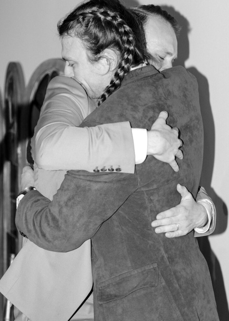 Groom hugs his brother during an emotional moment at the wedding reception.