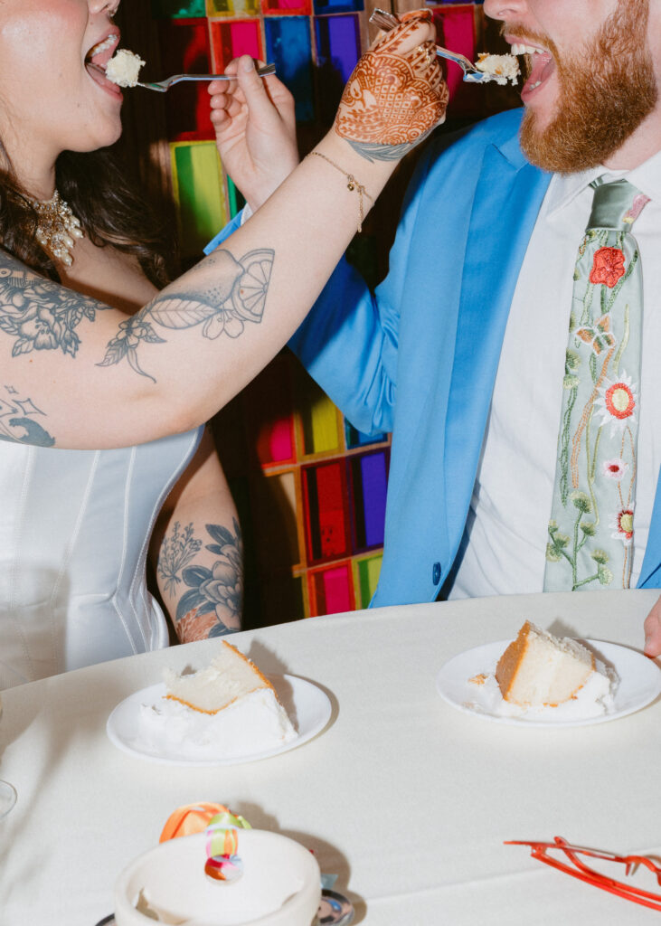 Close-up of the bride feeding the groom a bite of wedding cake during the reception.