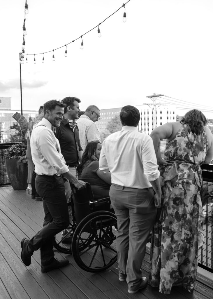 Black-and-white candid photo of wedding guests gathered on the rooftop patio at Solar Arts Building in Minneapolis.