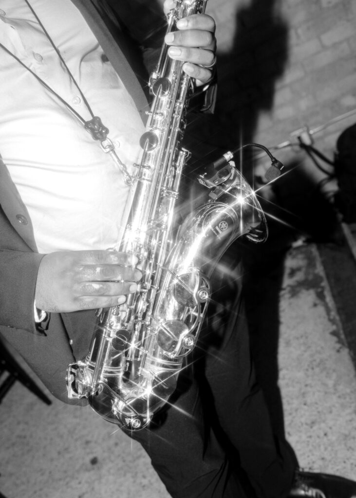 Black-and-white close-up of a saxophone player performing live during the wedding reception.